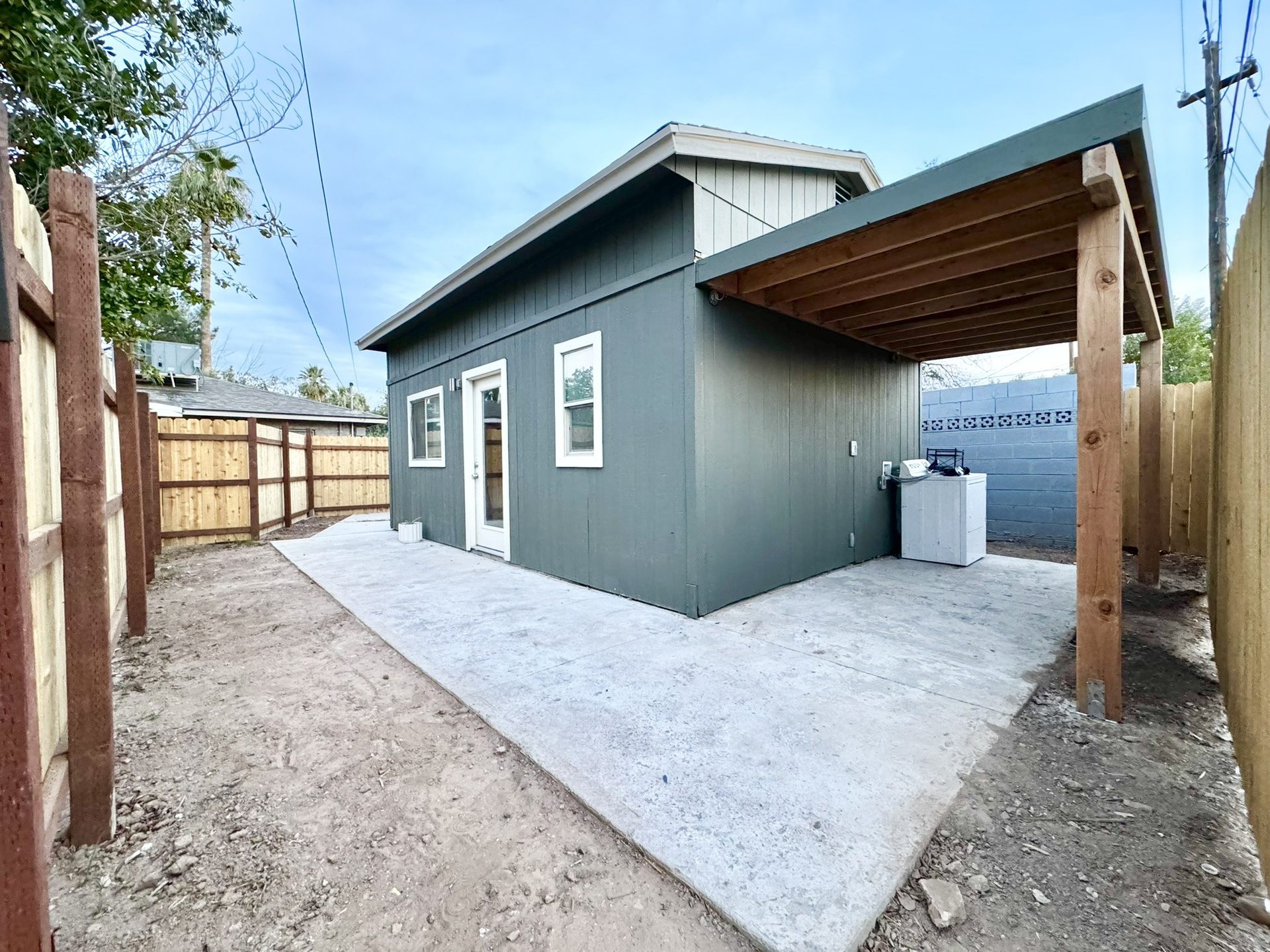 Repainted guest house with a new concrete patio and cedar privacy fence in a Tempe backyard