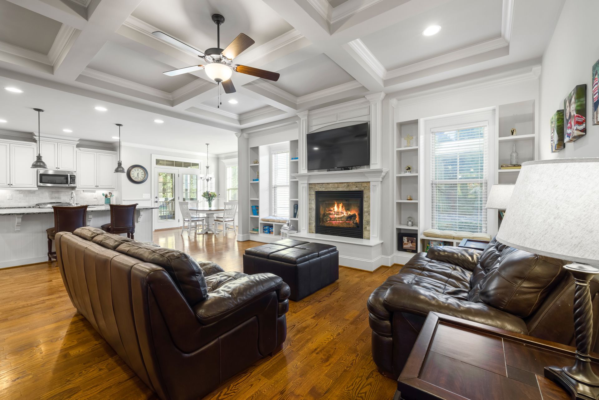 Oil-rubbed bronze five-blade ceiling fan with a frosted glass bowl light and pull chains in a family room with a coffered ceiling and recessed lights