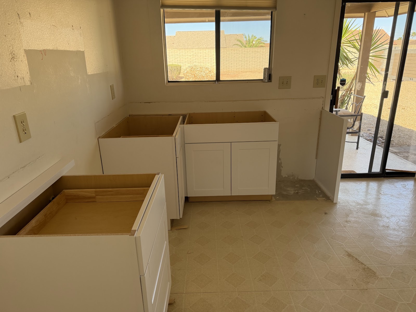New white base cabinets set and leveled along the sink wall of a Sun City West kitchen