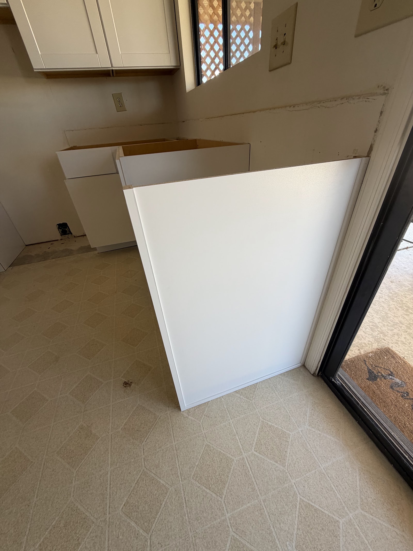 White finished end panel scribed to an out-of-square wall next to a sliding glass door in a kitchen