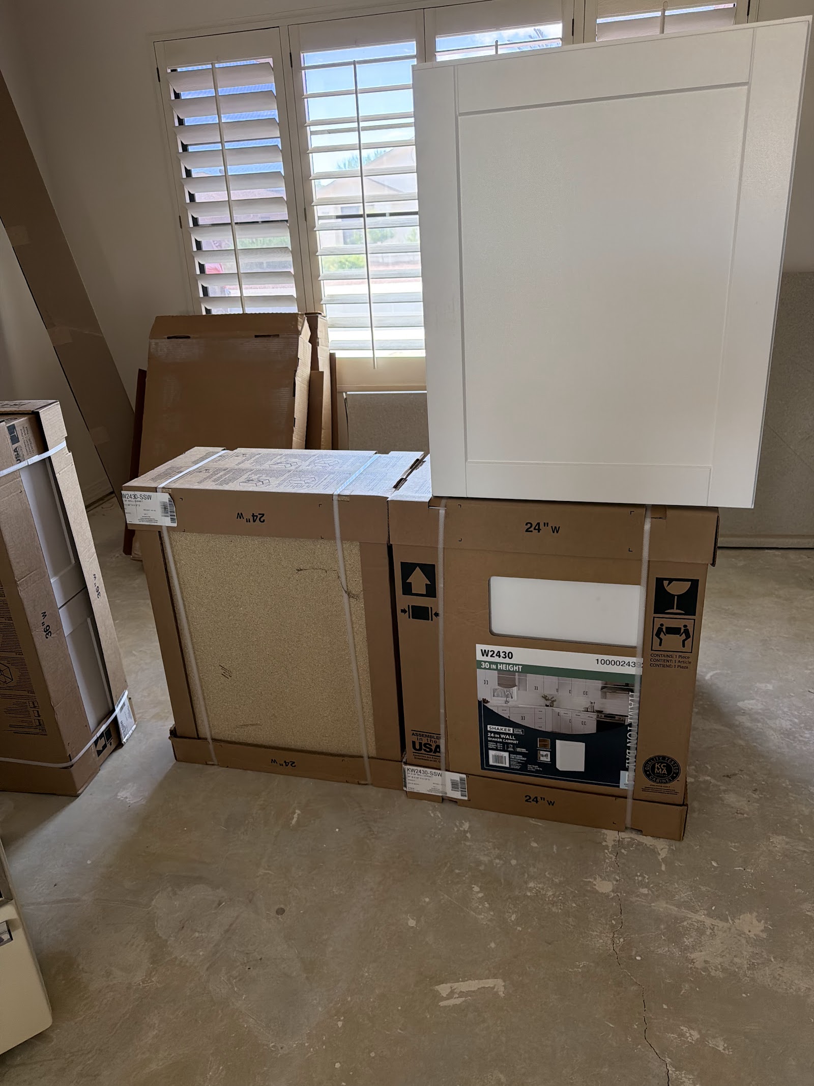 Hampton Bay Shaker satin white wall cabinets in boxes staged inside the house before installation