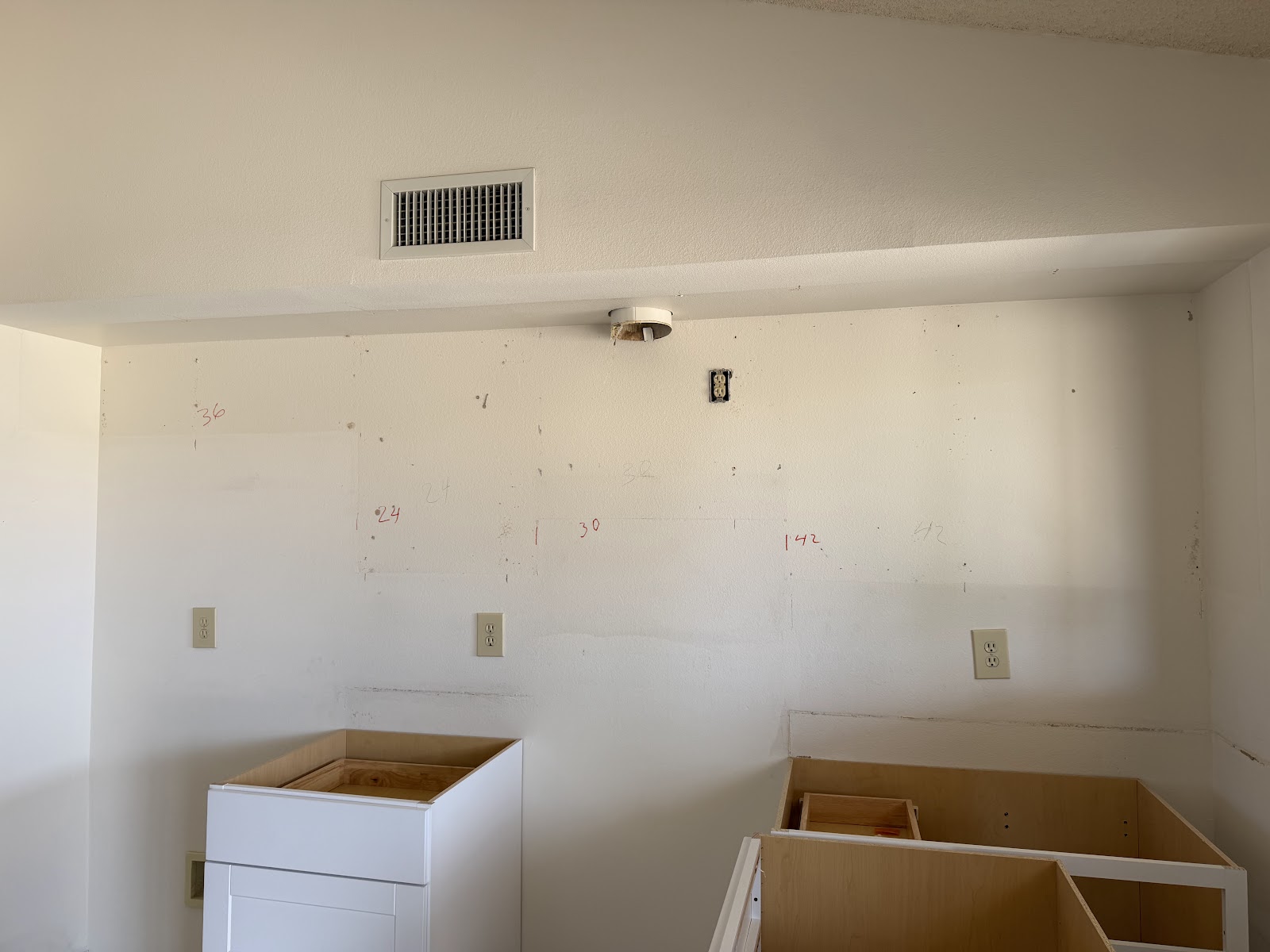 Red layout marks for 36, 30 and 42 inch cabinets drawn on the kitchen wall before hanging boxes