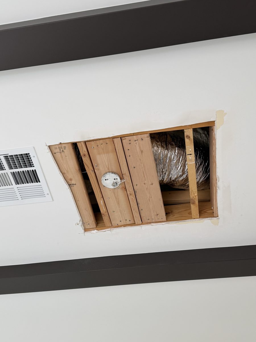 Solid 2x6 blocking screwed between the ceiling framing in a central Phoenix dining room, with a round fixture box mounted to it and insulated flex duct left undisturbed alongside