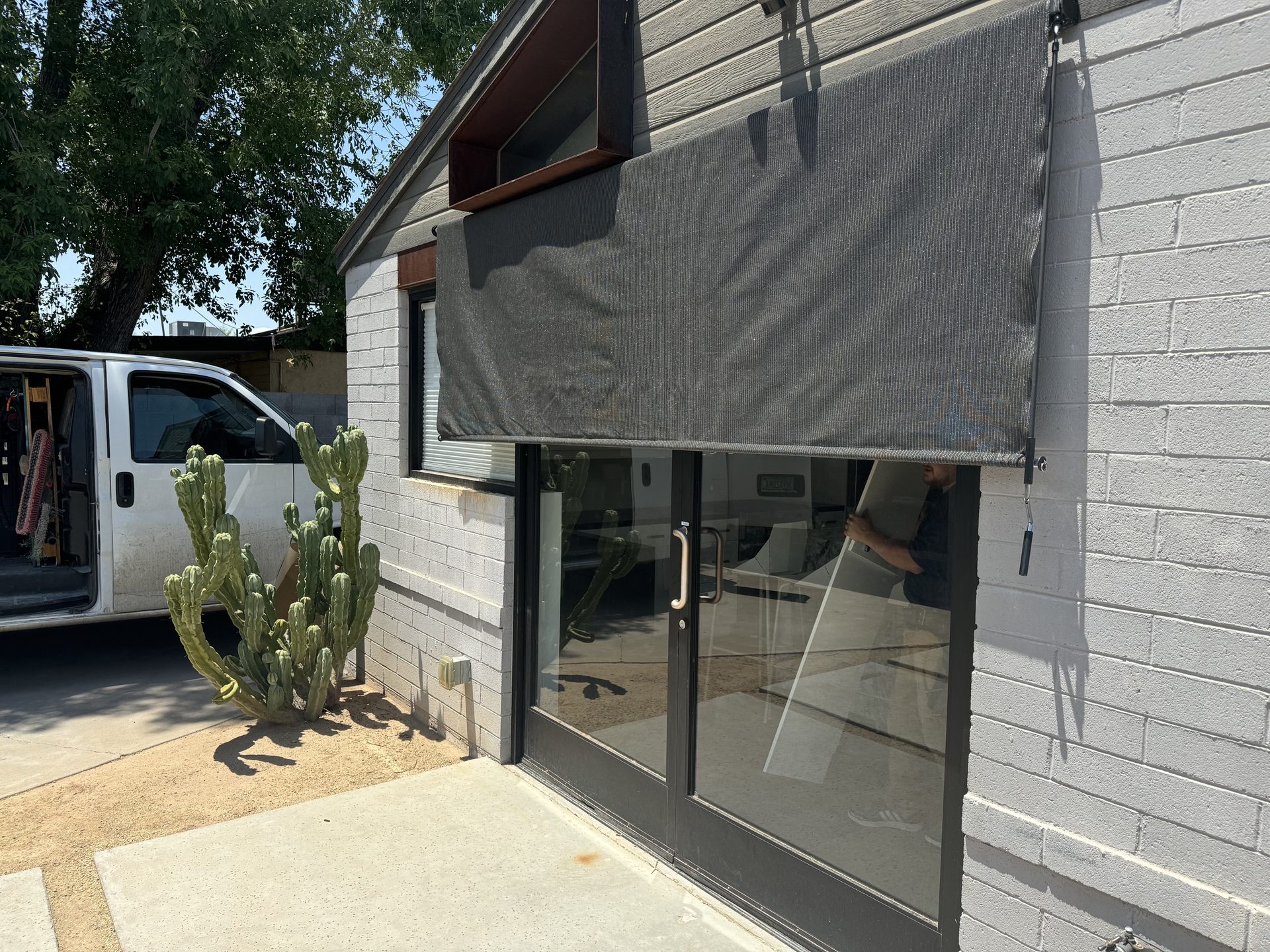 Coolaroo exterior roller shade deployed over black-framed glass double doors on a Phoenix property