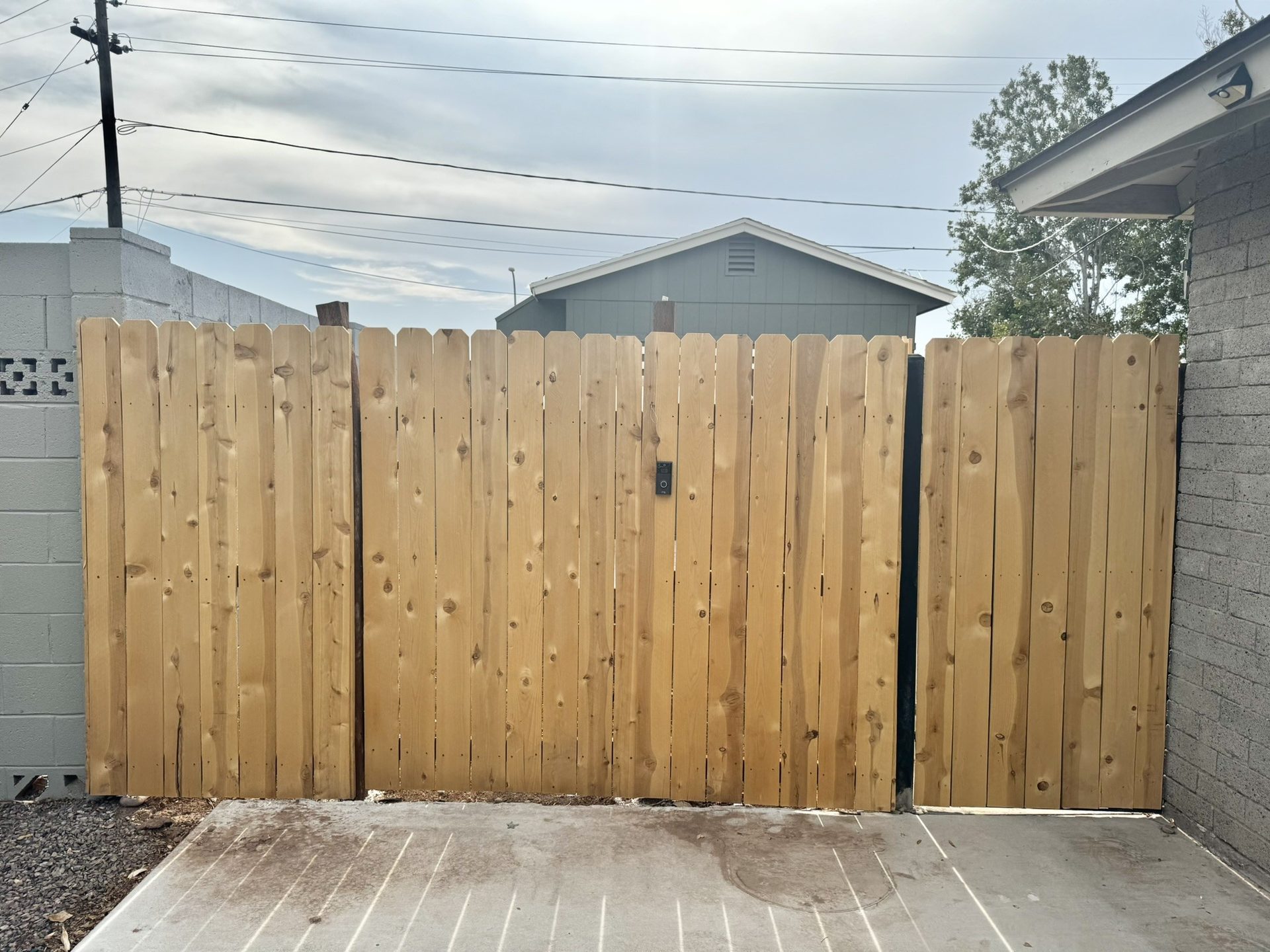 Matching cedar privacy gates blending into the fence line across a driveway in Tempe