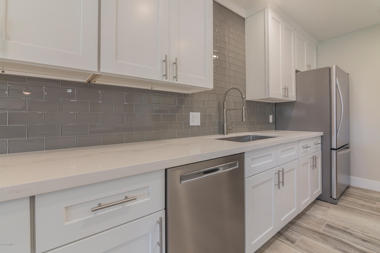 Flower Main House kitchen remodel in Phoenix: grey subway tile backsplash, quartz counter run, undermount sink with a spring-neck faucet and a stainless dishwasher