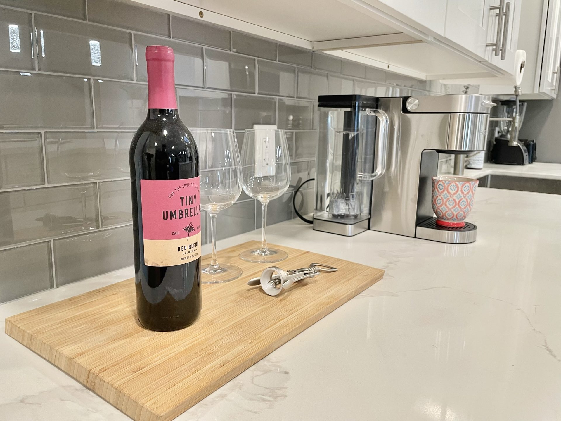 Flower Main House short-term rental in Phoenix: guest welcome setup on the quartz counter against the grey glass subway tile backsplash, with a coffee machine and blender