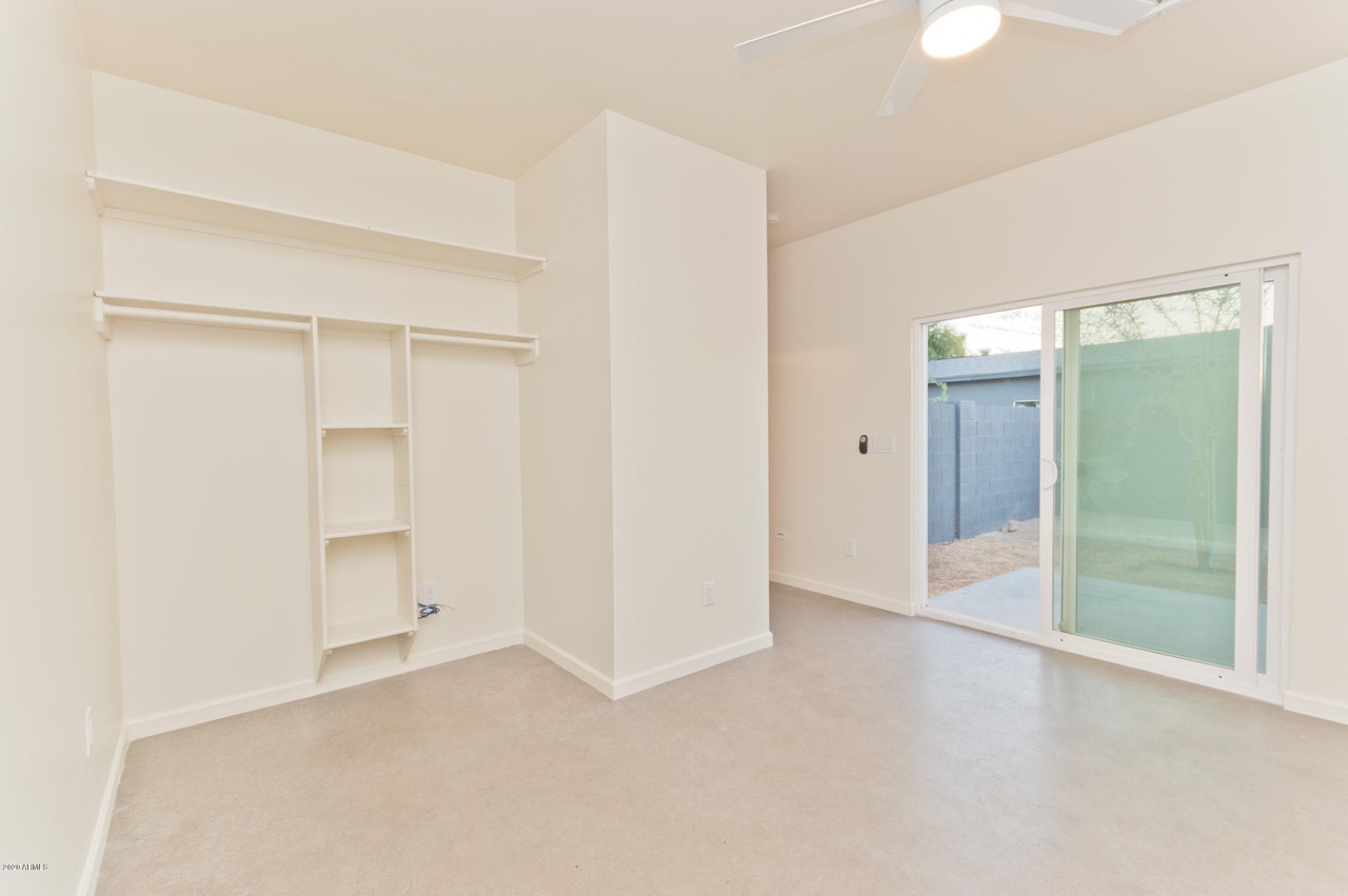 Guest house bedroom in Phoenix with open closet shelving, polished concrete floor and a slider to the patio