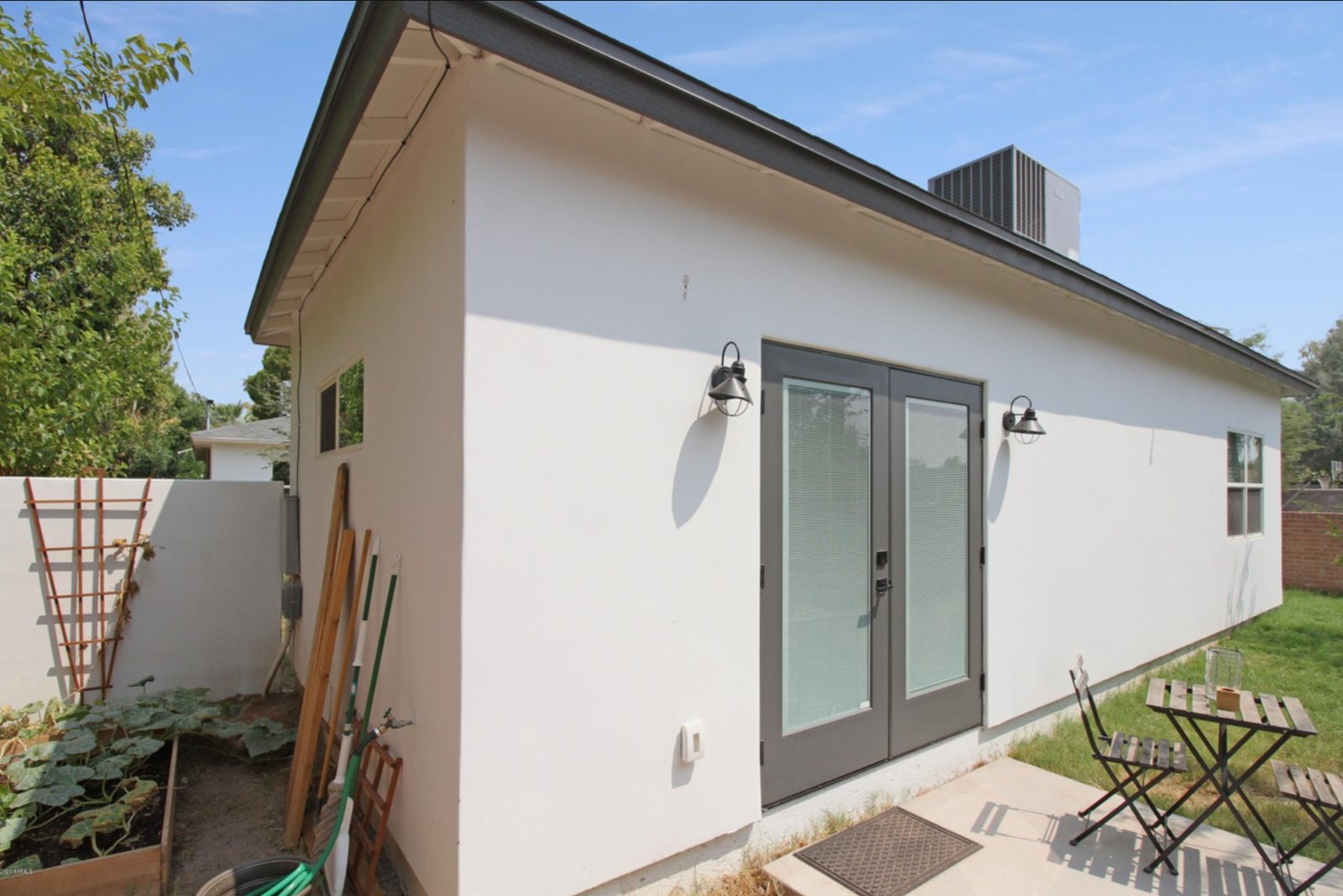 Side elevation of a detached stucco guest house in Phoenix with french doors and a rooftop condenser