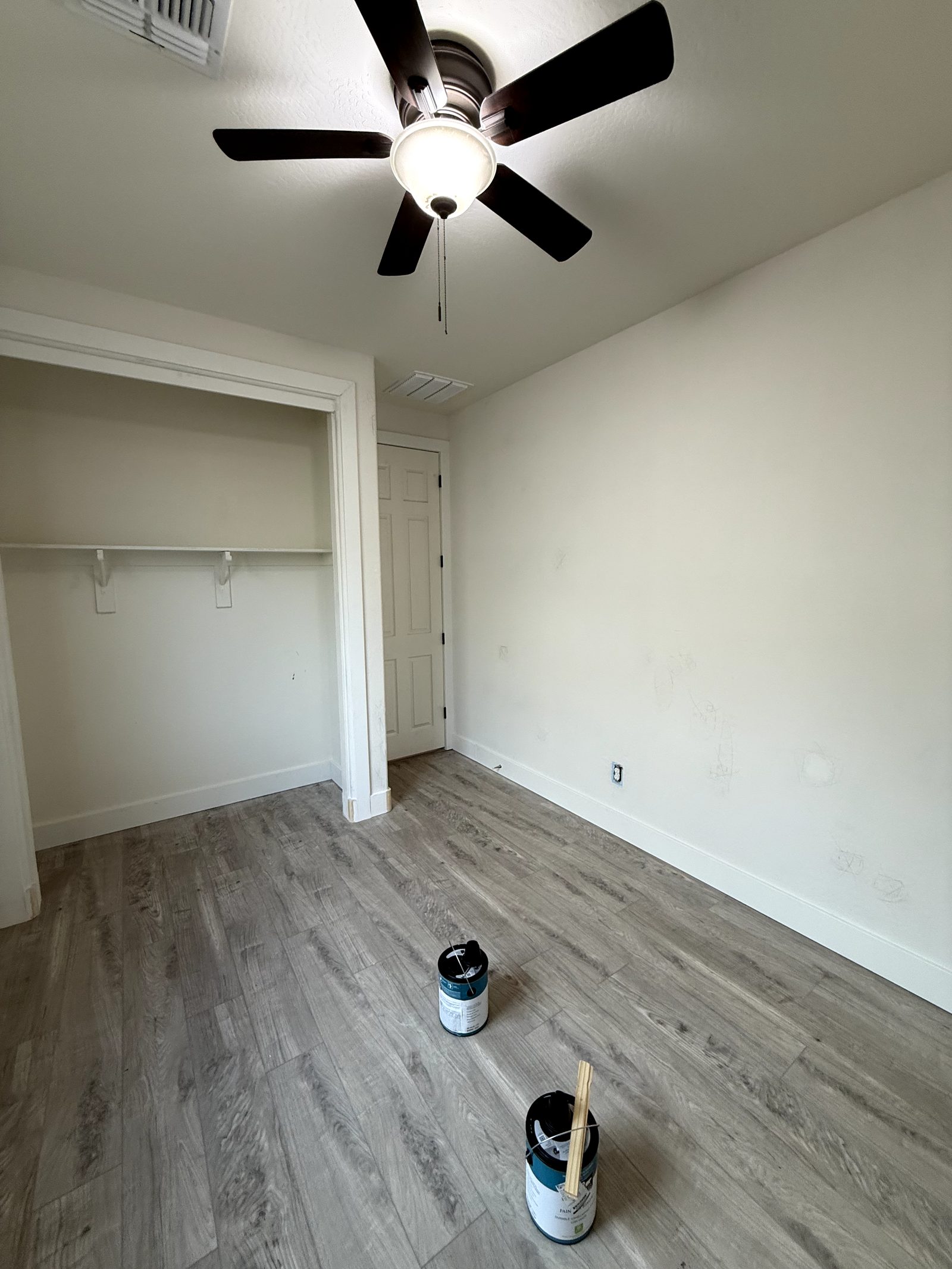 Empty bedroom after repainting, with freshly coated walls and ceiling, white trim and a wood look plank floor