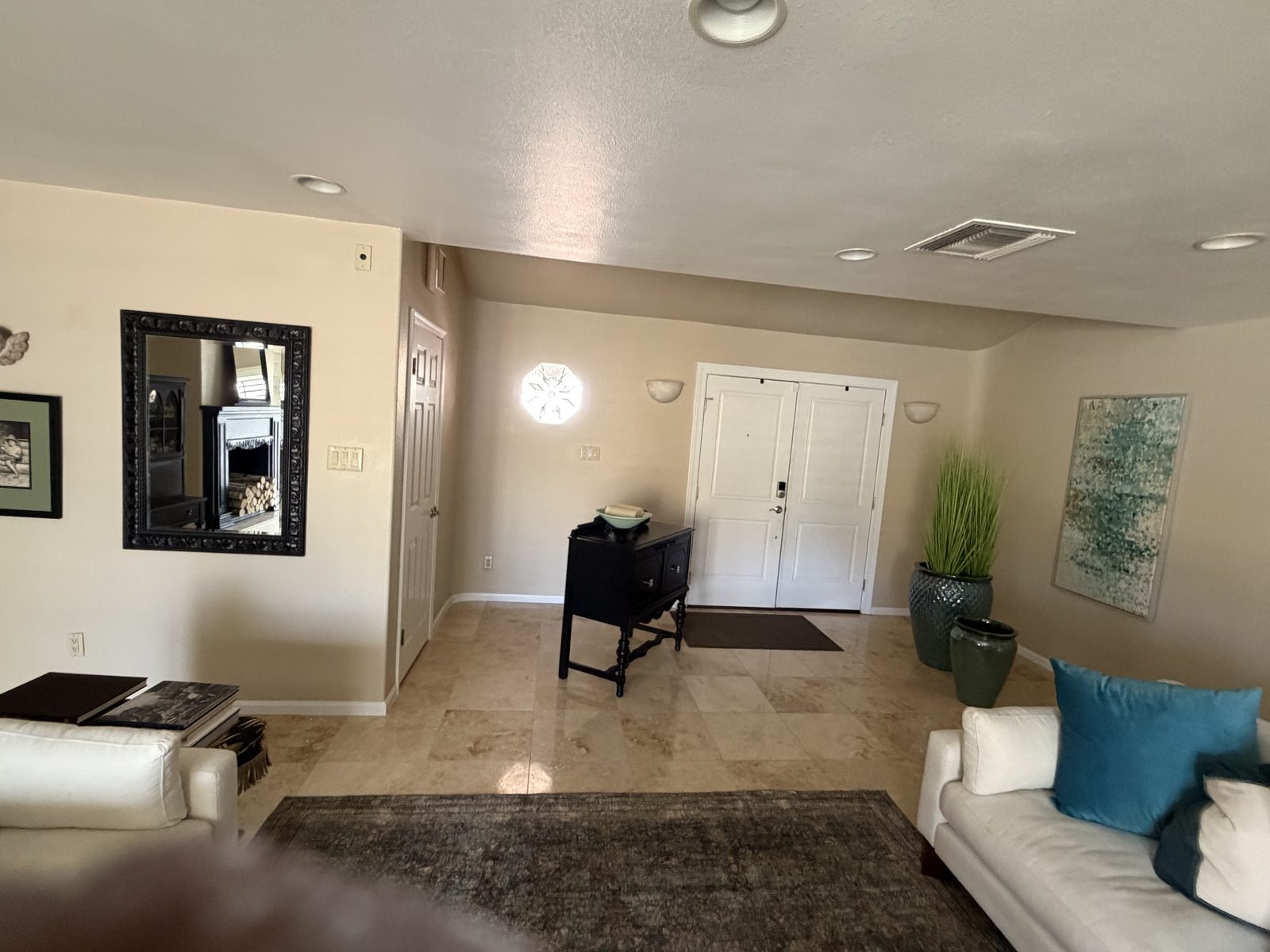Finished entry and living area with repainted white trim and casing around a front door, travertine floor and furniture still in the room