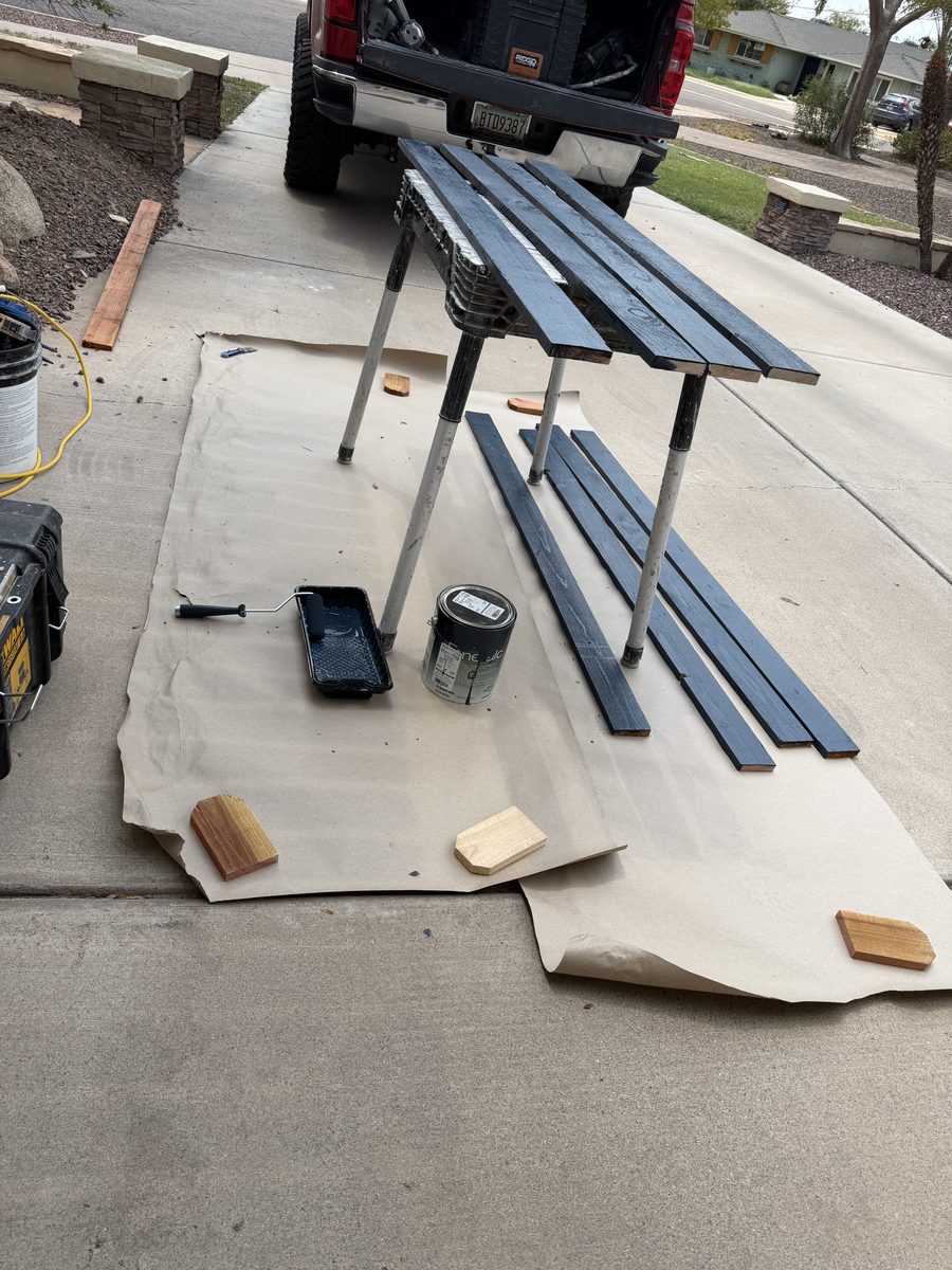 Iron flat bar laid out on drop cloths in a driveway for coating