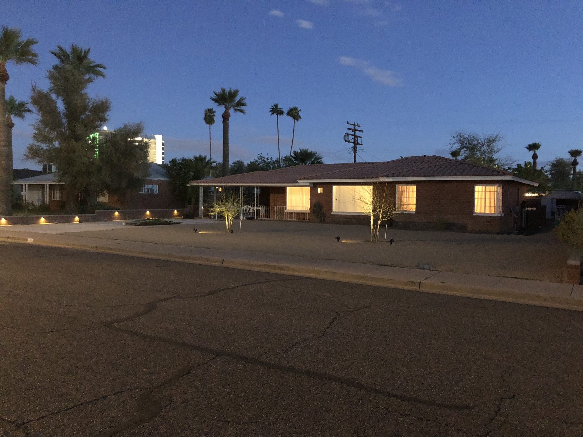 Low-voltage path lights and tree uplighting in a Phoenix desert front yard at dusk