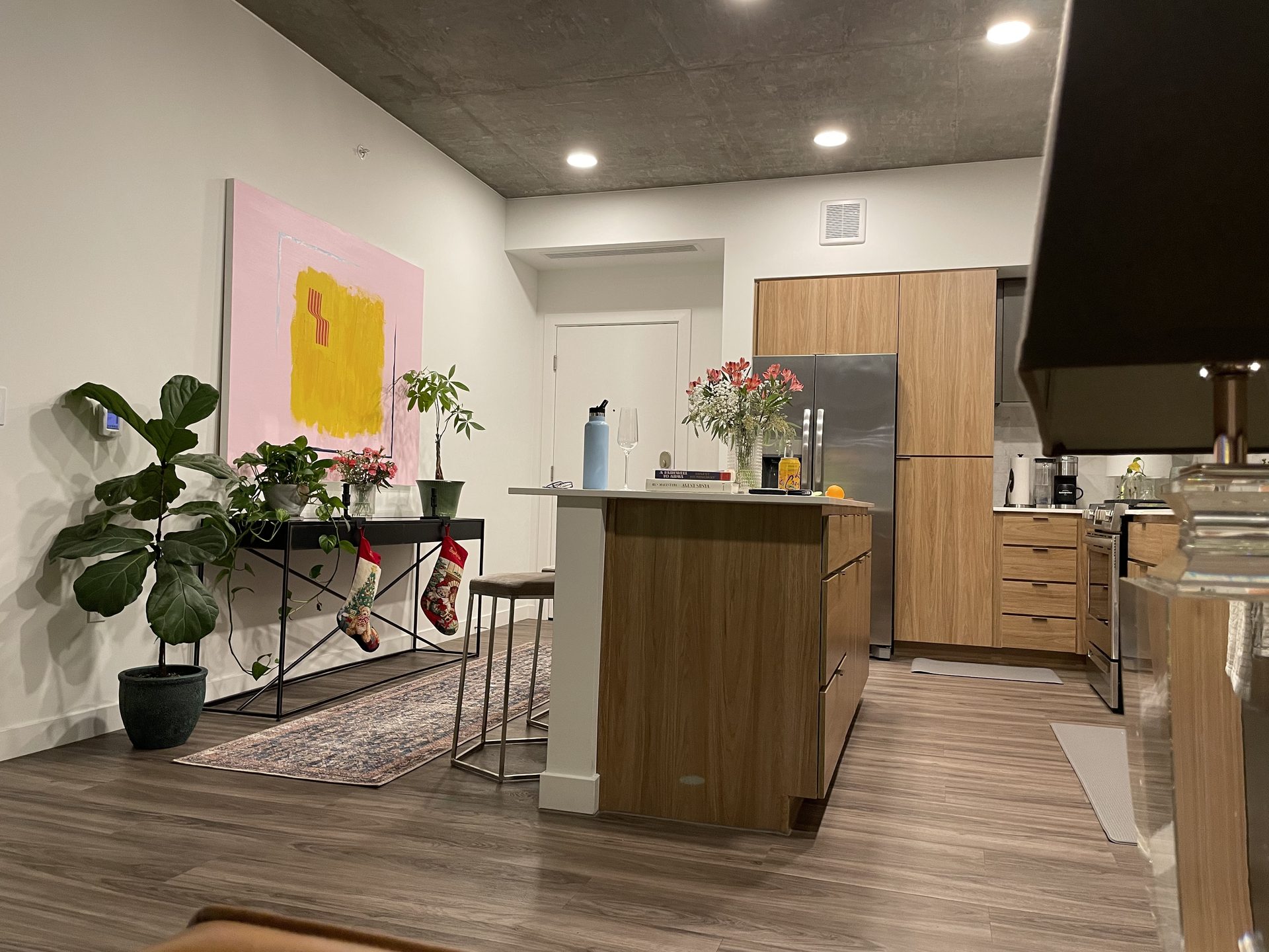 Large pink and yellow abstract canvas hung above a narrow black console table in the open kitchen and dining area of a downtown Phoenix condo