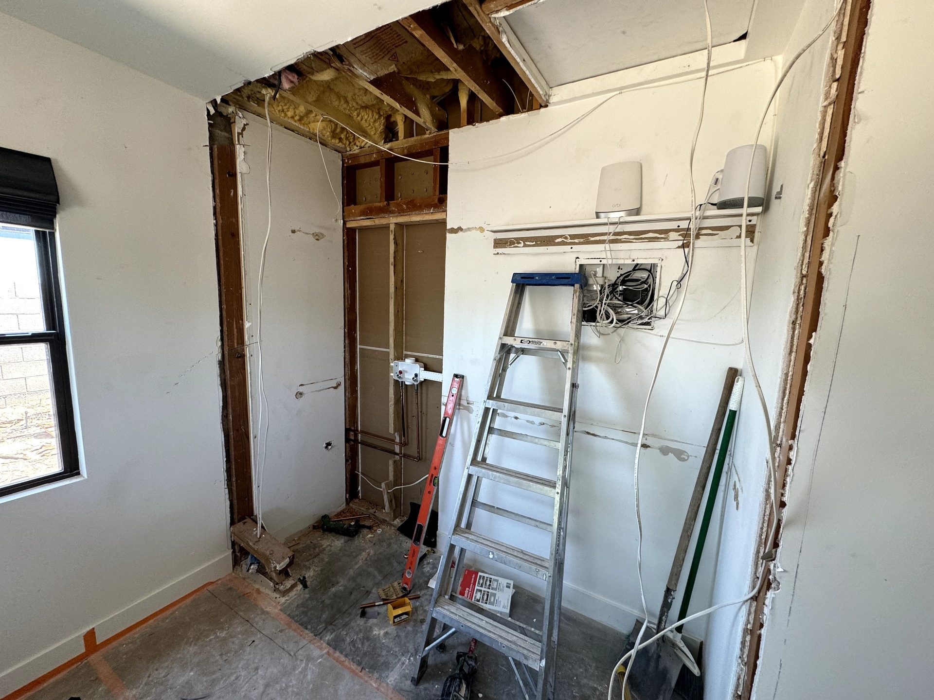 Closet wall opened up to exposed framing before adding laundry plumbing and power in Phoenix