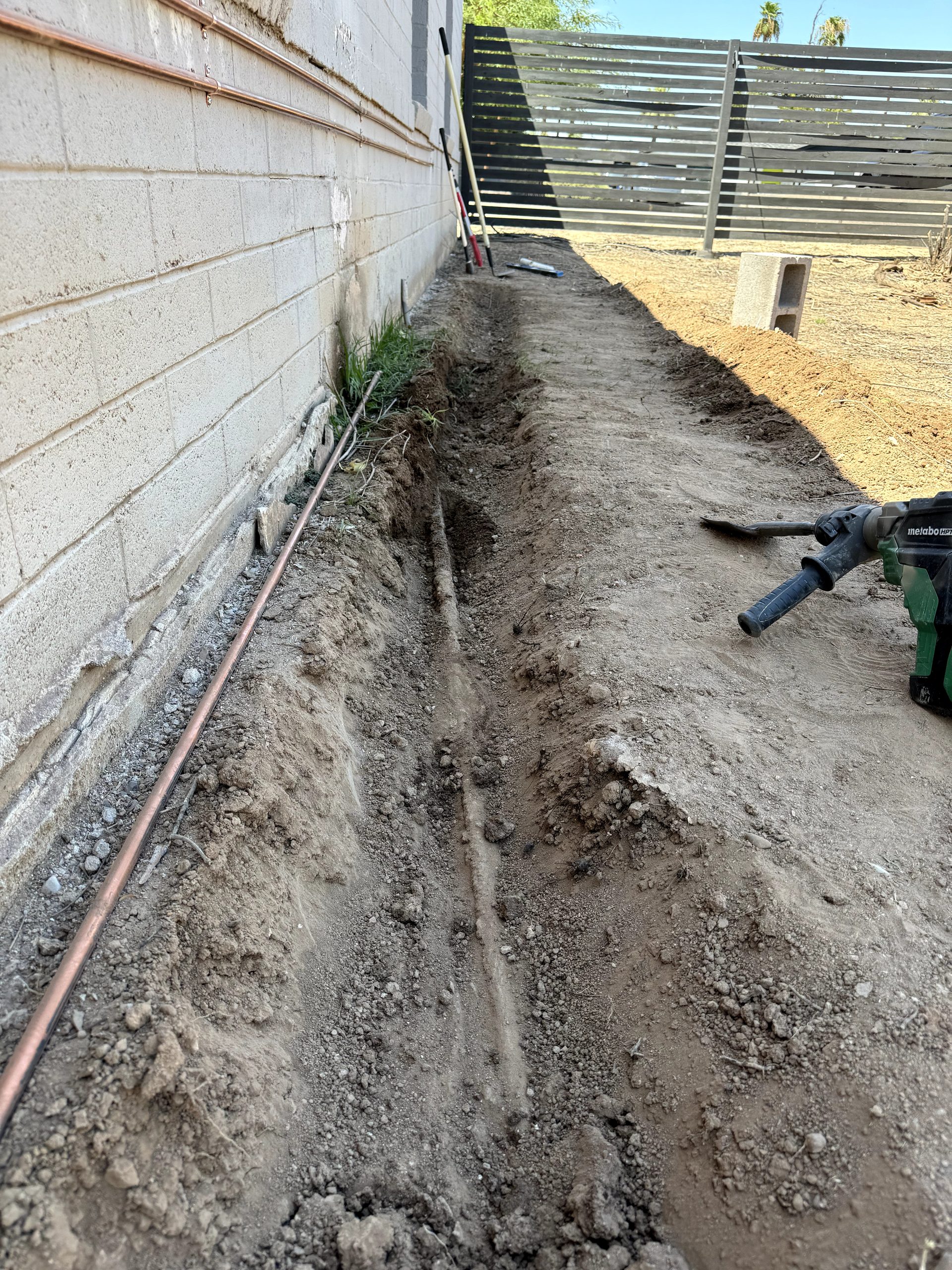 Trench along the exterior block wall for a new copper water line to a washer in Phoenix