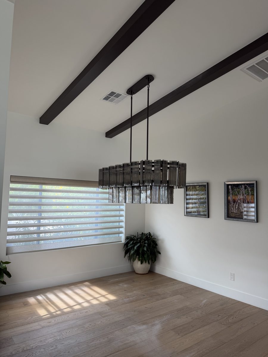 Oversized linear chandelier over a dining table under a vaulted beamed ceiling in central Phoenix