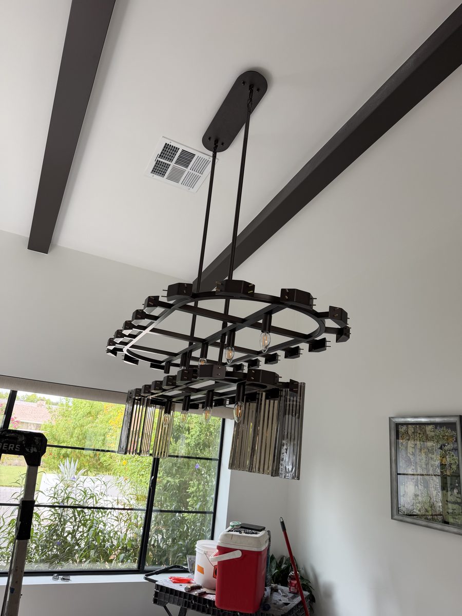 Oversized linear glass-rod chandelier hung from the vaulted ceiling in a central Phoenix dining room, viewed from below against the dark faux beams