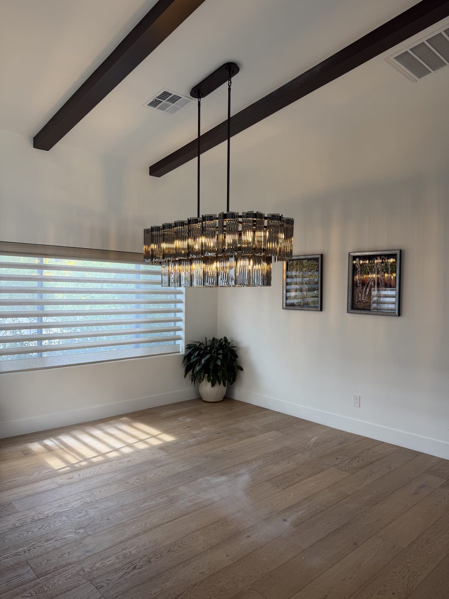Finished central Phoenix dining room with the oversized linear chandelier over the table, wood floors and vaulted beamed ceiling