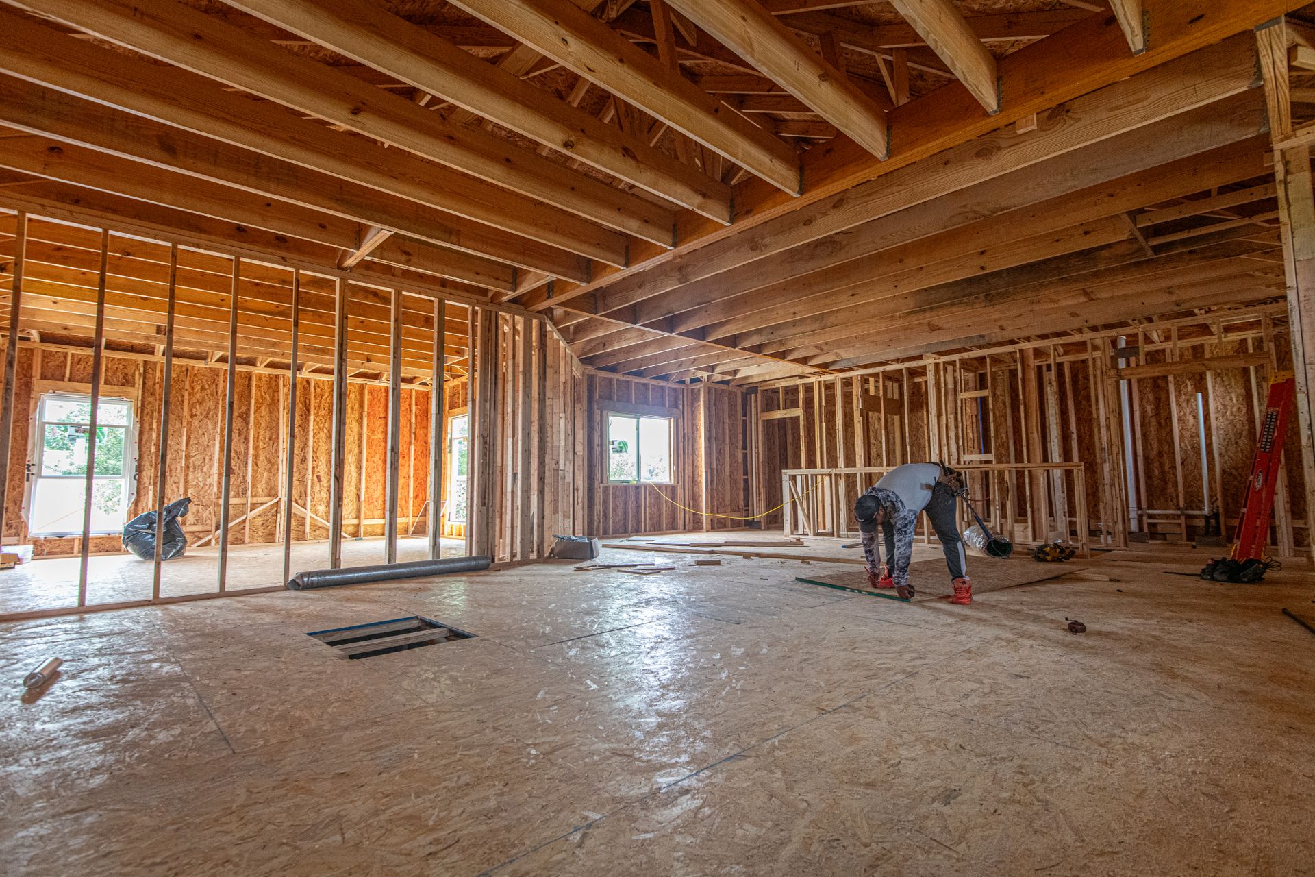 New 2x4 interior partition walls framed on a wood subfloor under exposed ceiling framing, with a floor register opening cut nearby