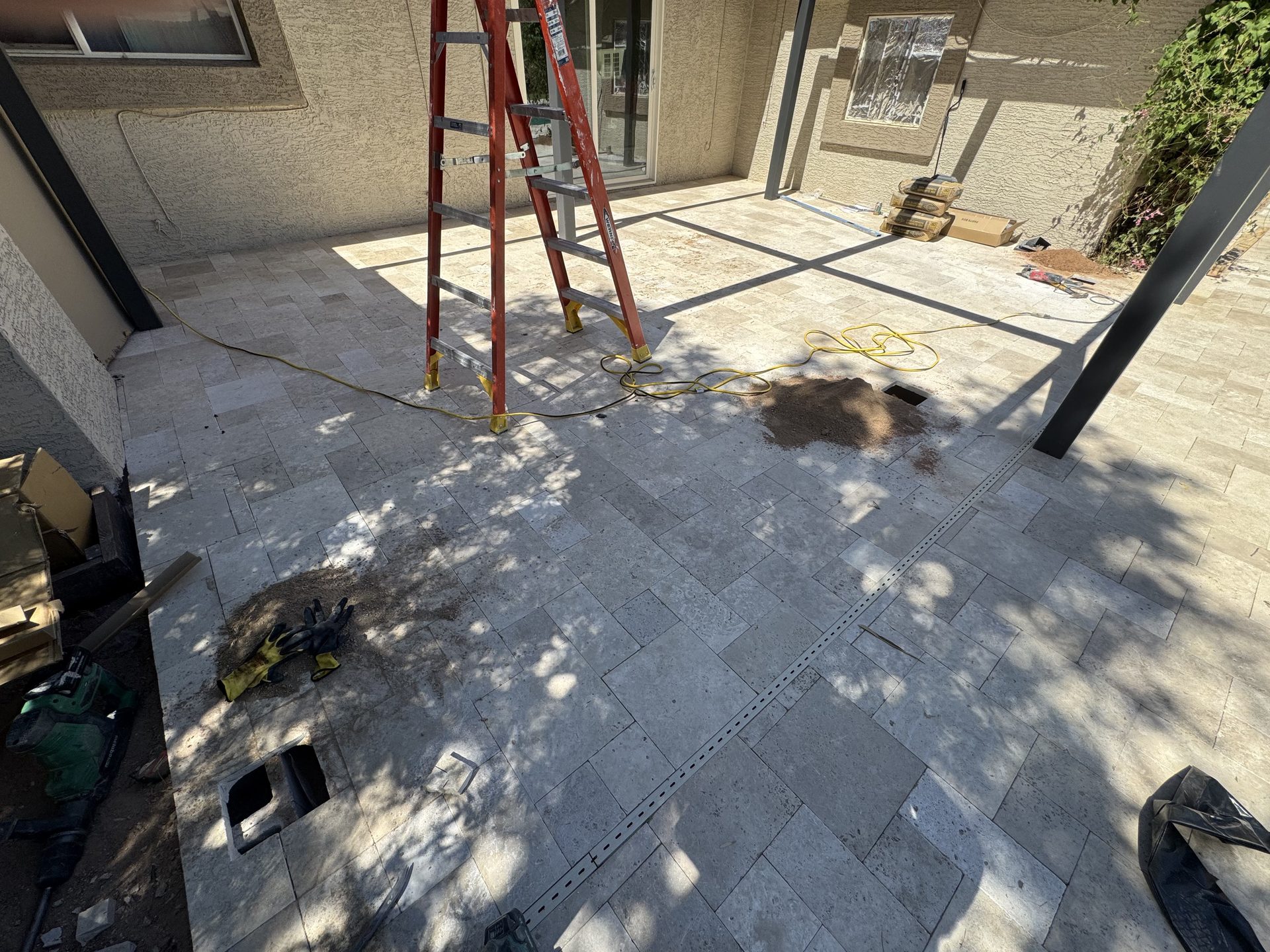Concrete footings cut through a paver patio for pergola posts in Phoenix