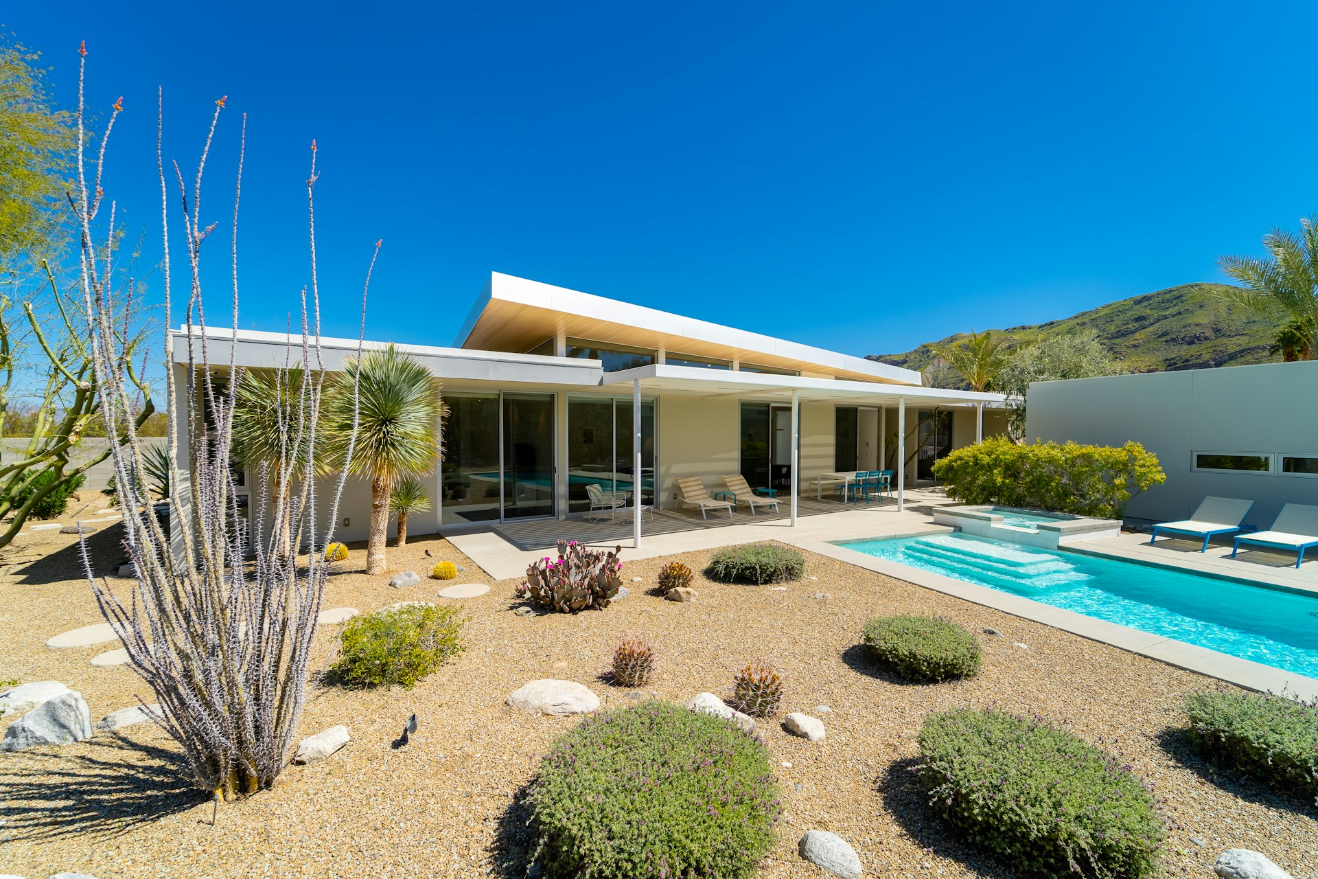 Light concrete pool deck beside a desert modern home