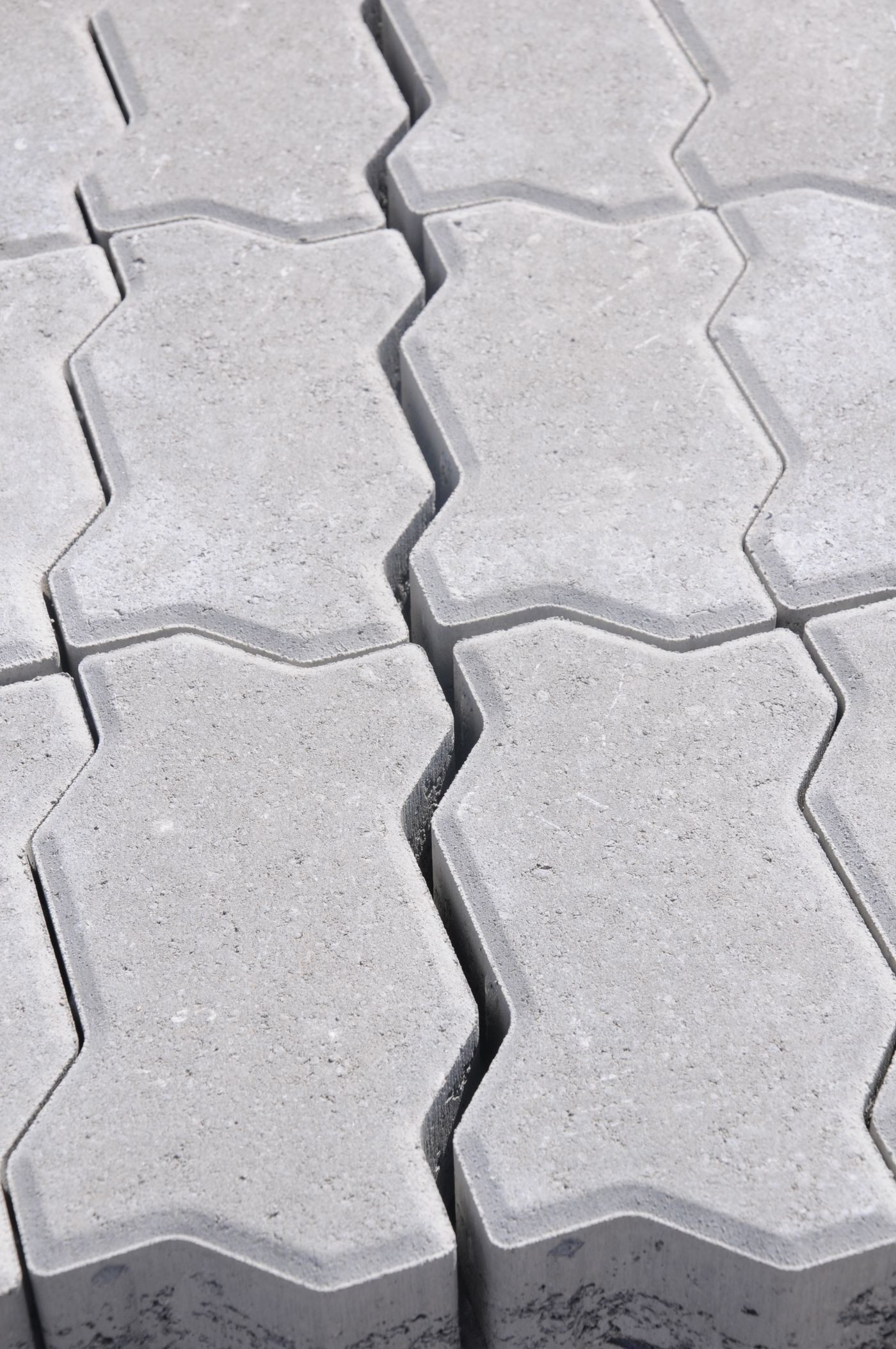 Interlocking concrete pavers laid in a wavy pattern, with the bedding layer visible at the open edge of the field
