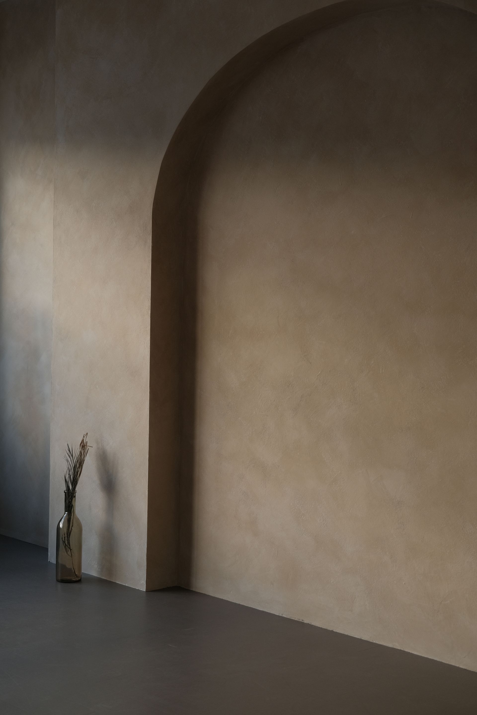 Arched interior wall in a warm taupe clay plaster with a soft matte suede surface