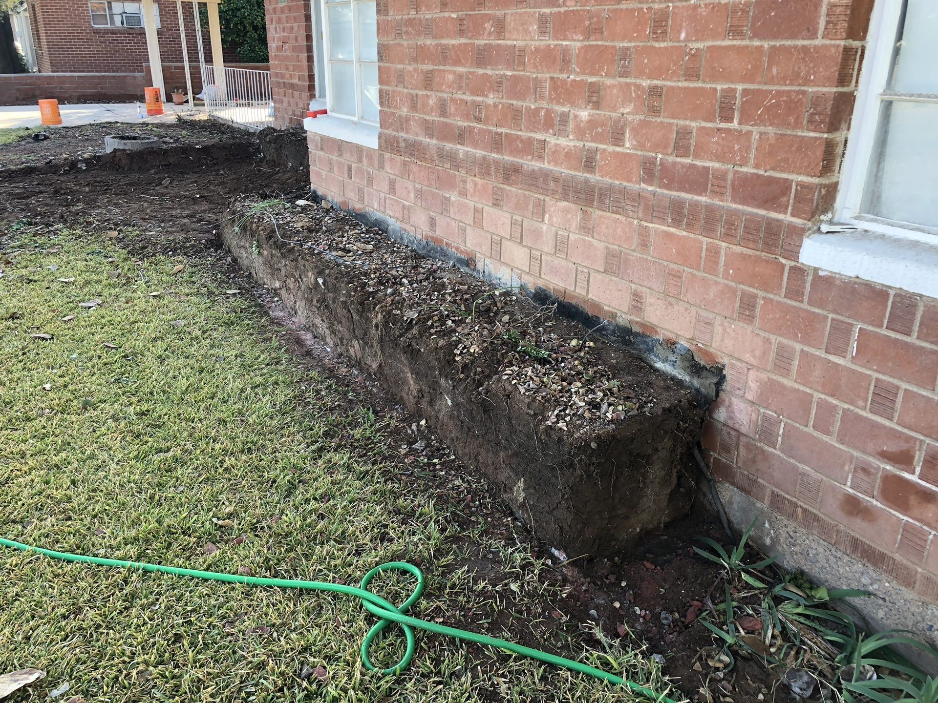 Raised planter removed from against a brick house wall in Phoenix to restore drainage
