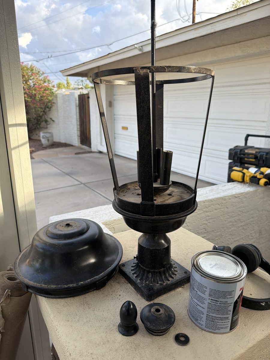 Pier-mount lantern taken apart into hood, cage and base for refinishing on a stone column