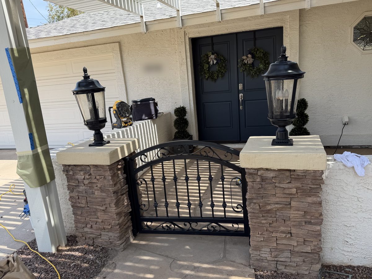 Refinished black iron gate and pier lanterns at a Phoenix flagstone courtyard entry