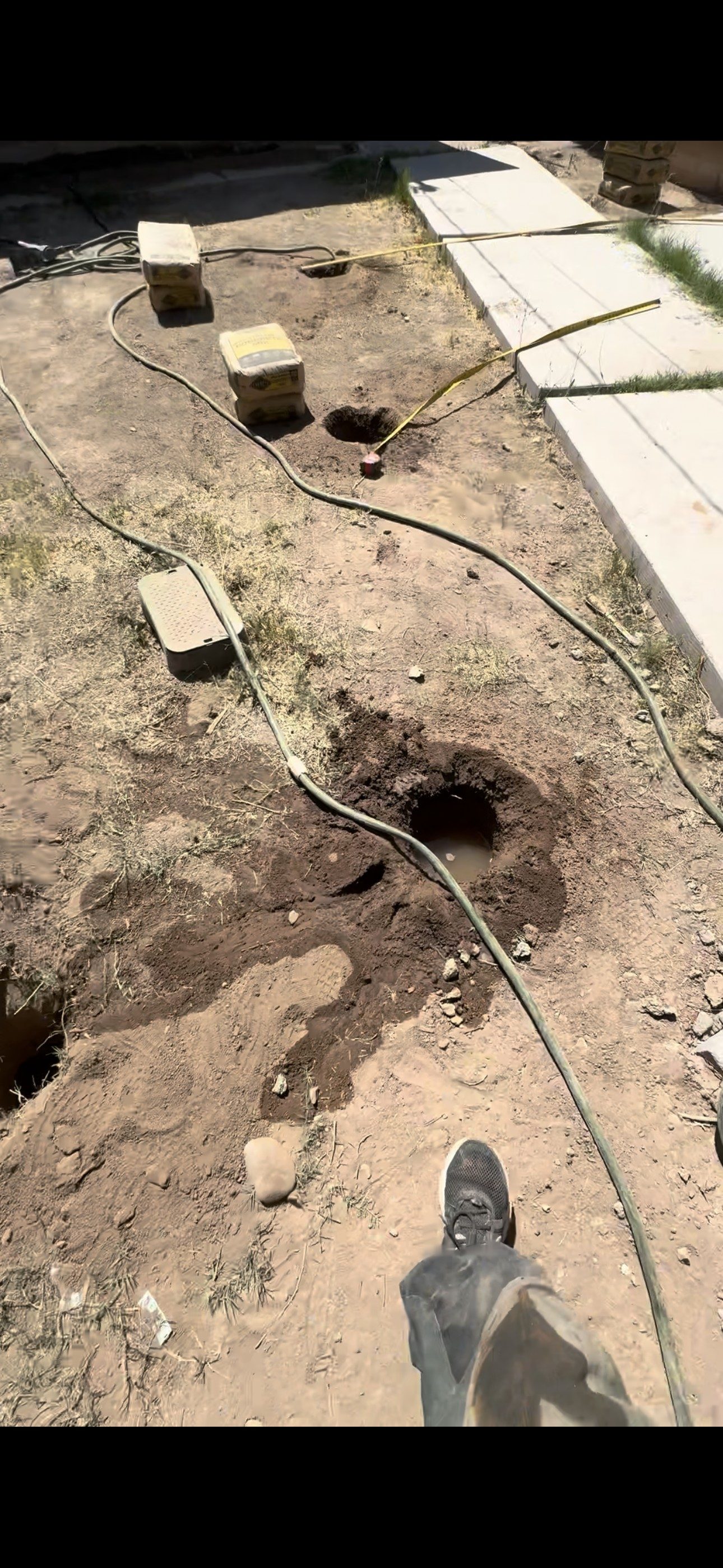 Fence post hole pre-soaked to dig through hard caliche soil in Tempe, Arizona