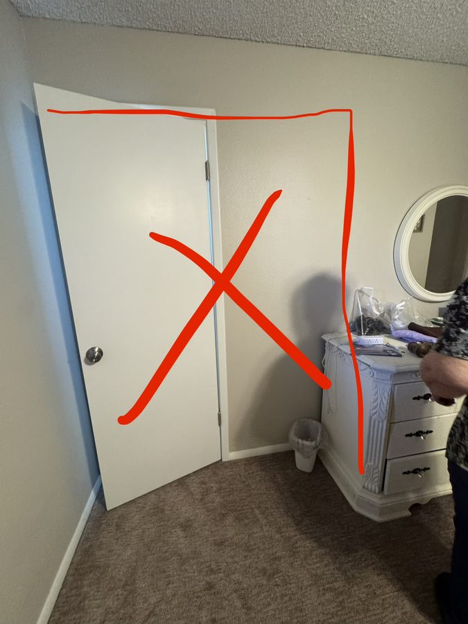 Original narrow master bathroom door in a Mesa home, marked for removal to widen the entry for wheelchair access