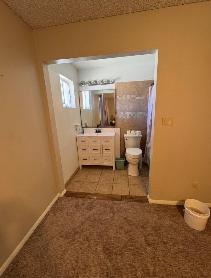Finished wheelchair-accessible master bathroom entry with curbless tile transition in Mesa, AZ