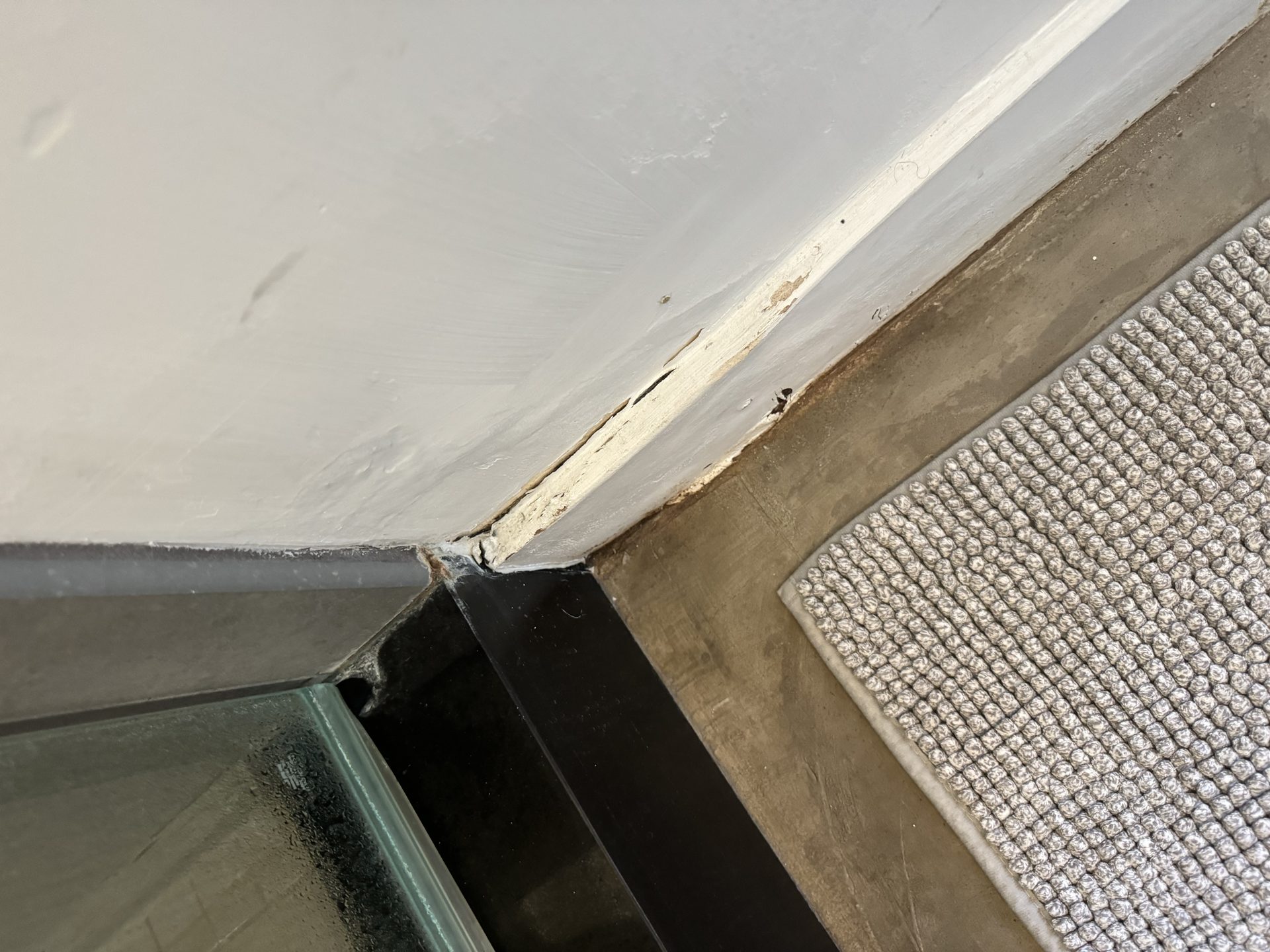 Water damage on the baseboard outside the shower, the first evidence of a failed shower pan