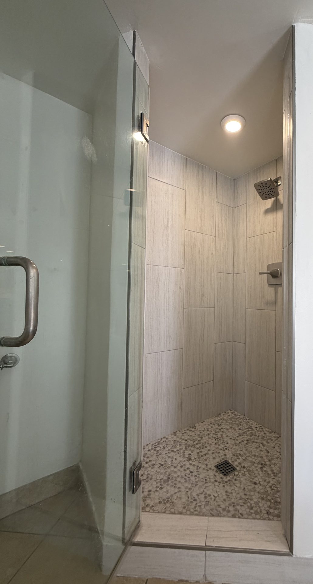 Finished shower interior with vertical porcelain plank walls, penny-round pan and new brushed nickel shower head, Scottsdale AZ