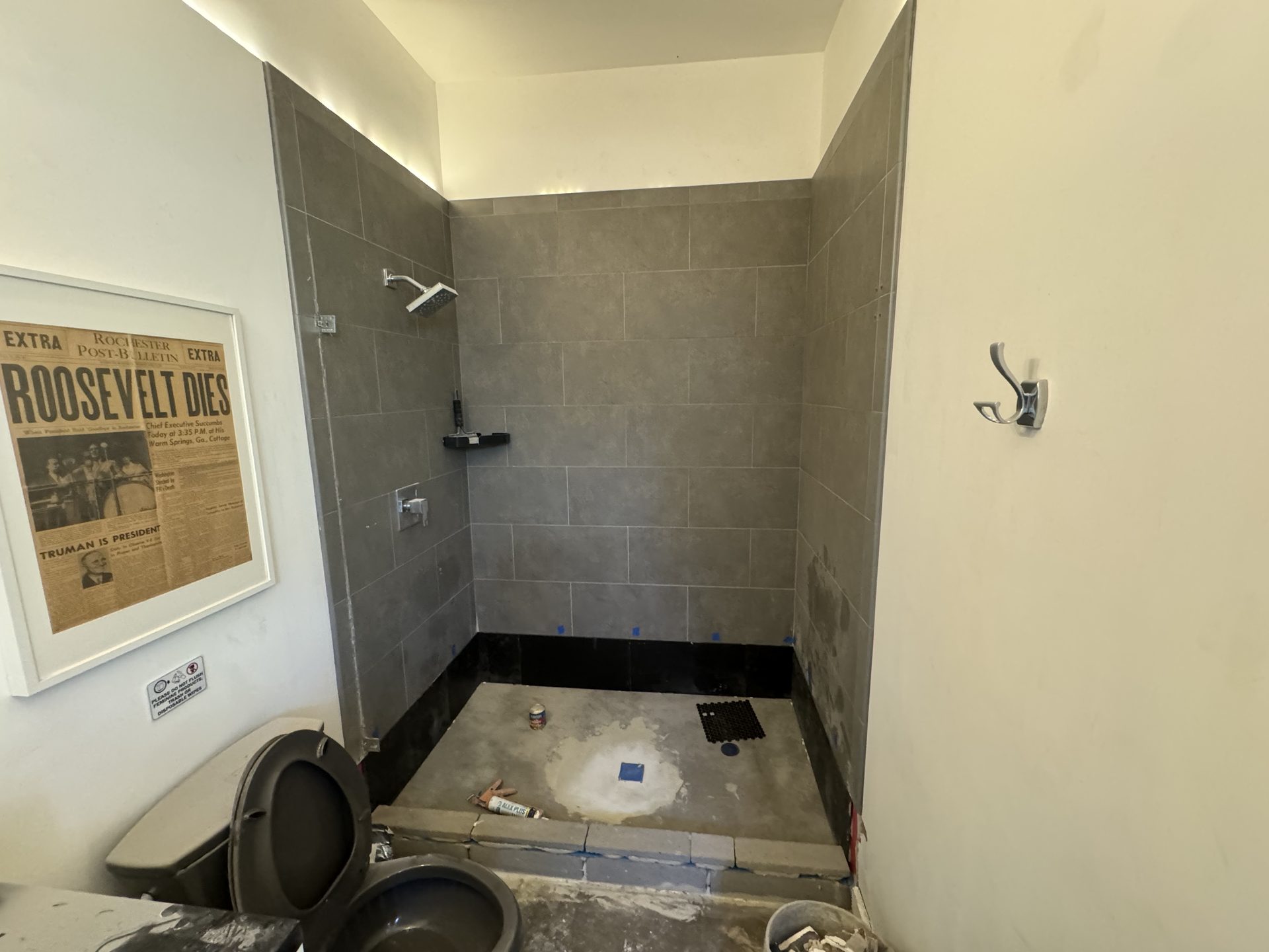 Shower pan rebuild in progress with the existing gray wall tile saved and the new pan bed curing