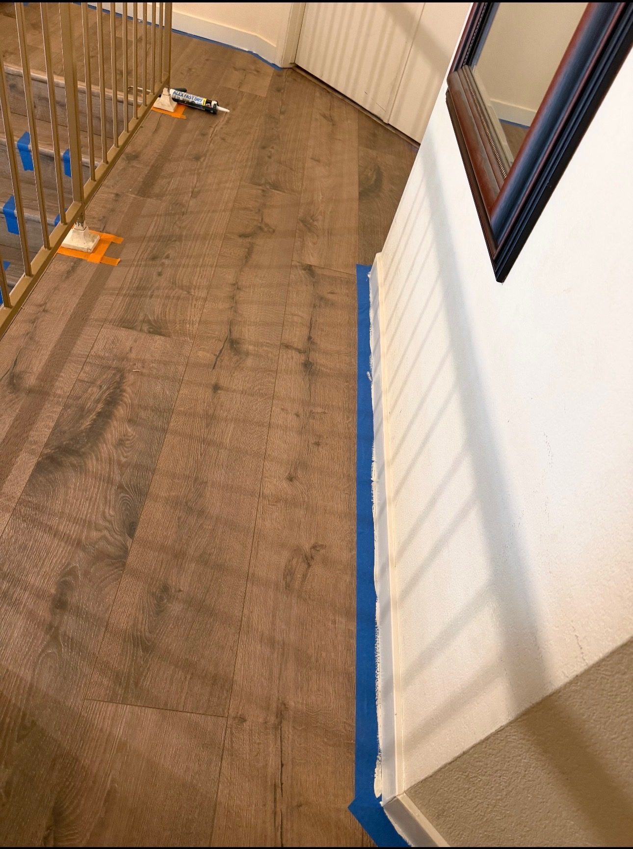 During: vinyl plank installed on second-floor landing, baseboards taped for paint Phoenix AZ