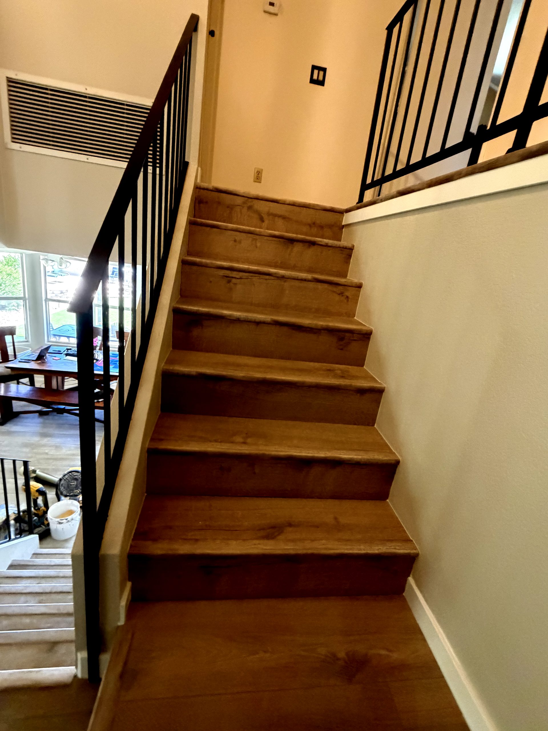After: full staircase in wood-look vinyl plank with black-painted railing Phoenix AZ