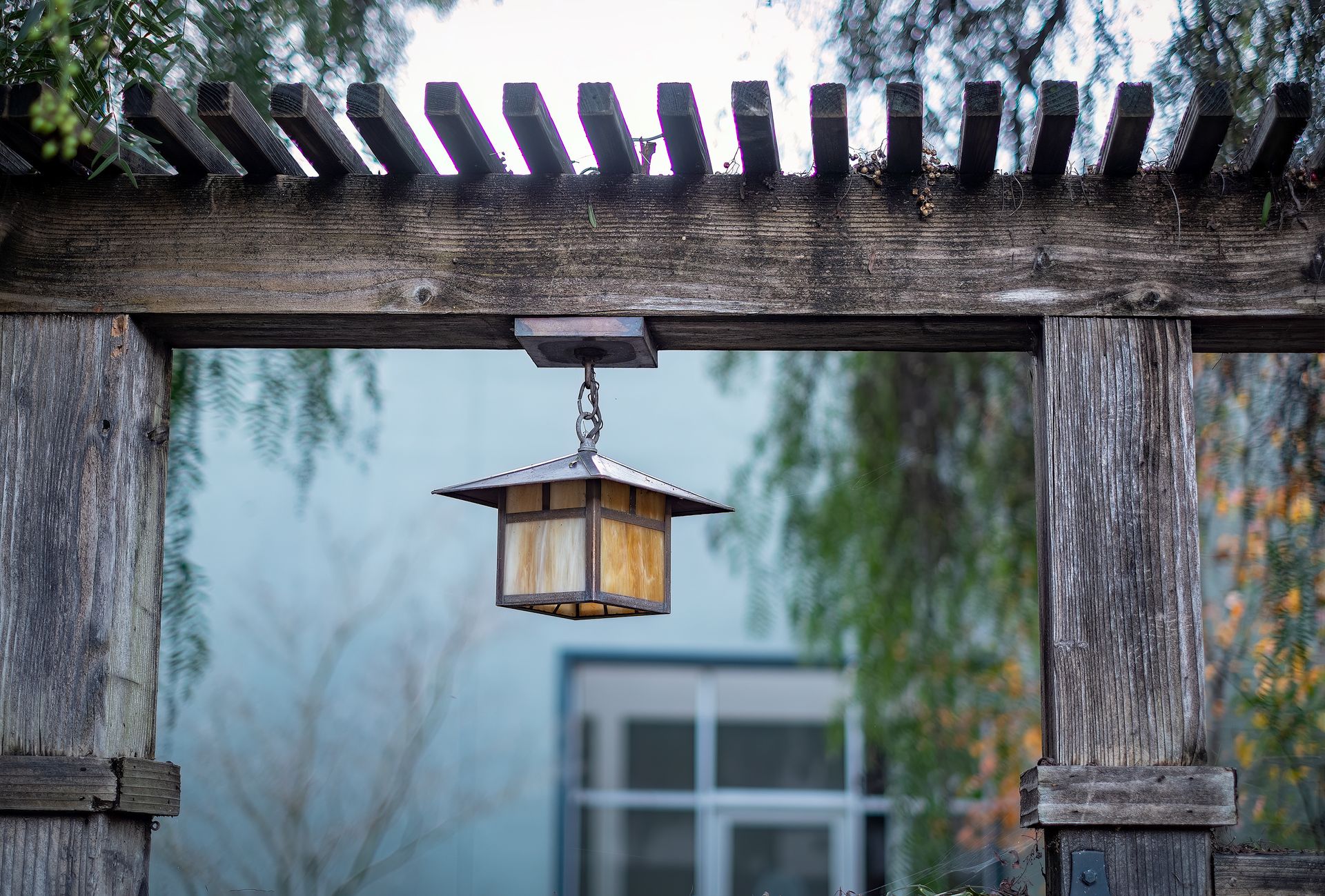 A weathered gray wood header beam with surface checks and splits along its length, resting on two square posts under a row of rafter tails